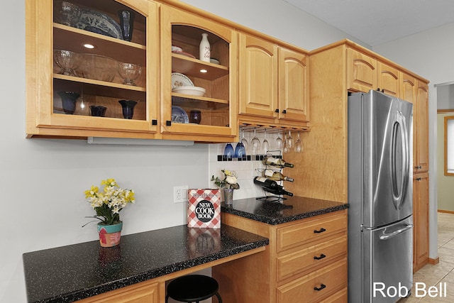 4524 Hidden Ridge Dr, Hudsonville, MI 49426 - kitchen with freestanding refrigerator, backsplash, dark stone countertops, glass insert cabinets, and light brown cabinetry