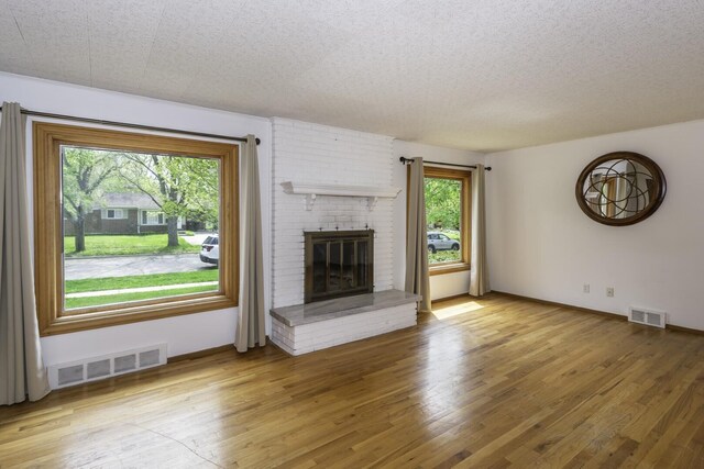 1620 Whittier Rd, Ypsilanti, MI 48197 - unfurnished living room featuring light wood-style flooring, a fireplace, baseboards, and a textured ceiling