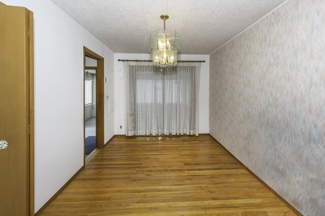 1620 Whittier Rd, Ypsilanti, MI 48197 - unfurnished dining area featuring wood finished floors, a chandelier, and wallpapered walls