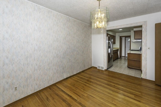 1620 Whittier Rd, Ypsilanti, MI 48197 - unfurnished dining area with light wood-type flooring, a chandelier, wallpapered walls, and baseboards