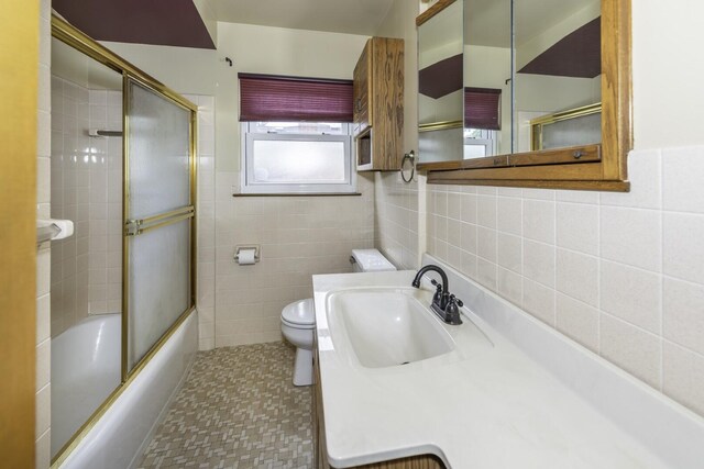 1620 Whittier Rd, Ypsilanti, MI 48197 - bathroom with tile walls, toilet, combined bath / shower with glass door, and vanity