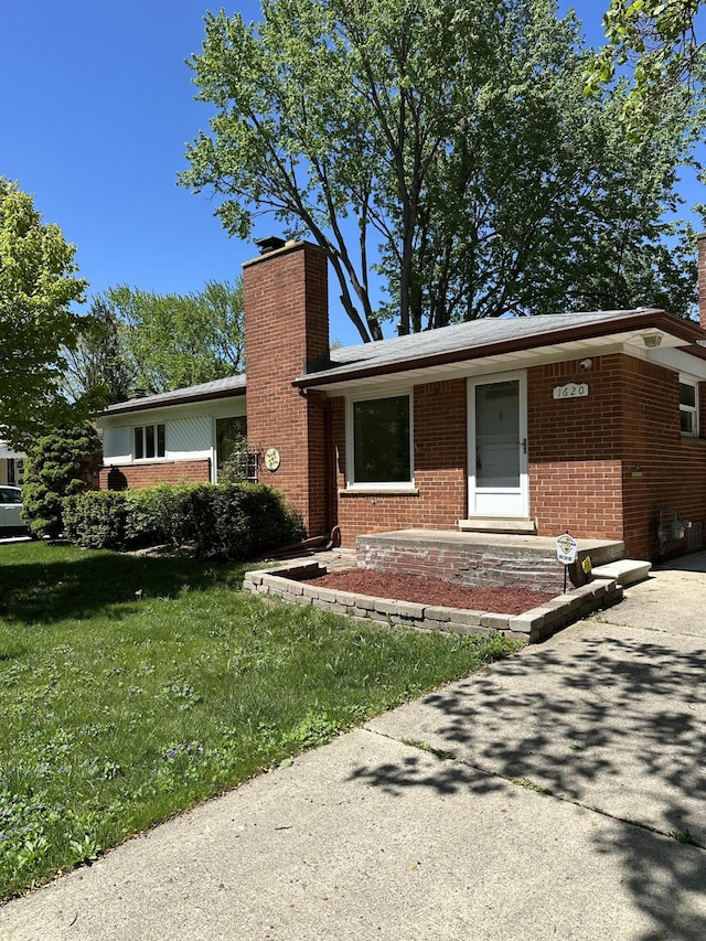 1620 Whittier Rd, Ypsilanti, MI 48197 - ranch-style home with a chimney, brick siding, and a front yard