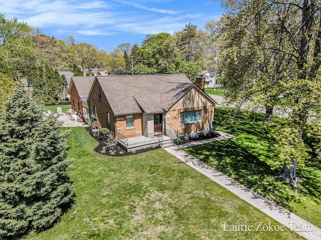 347 Dewitt Ln, Spring Lake, MI 49456 - view of front of house featuring a chimney, brick siding, a front yard, roof with shingles, and view of wooded area