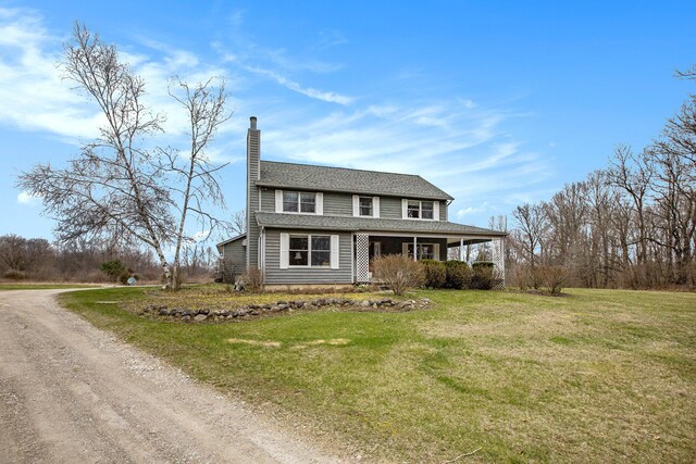 view of front of property featuring driveway, a chimney, and a front yard