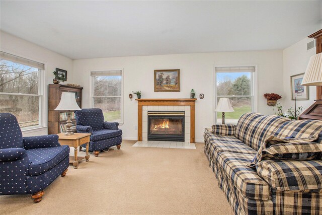 living room with a tiled fireplace, baseboards, plenty of natural light, and carpet