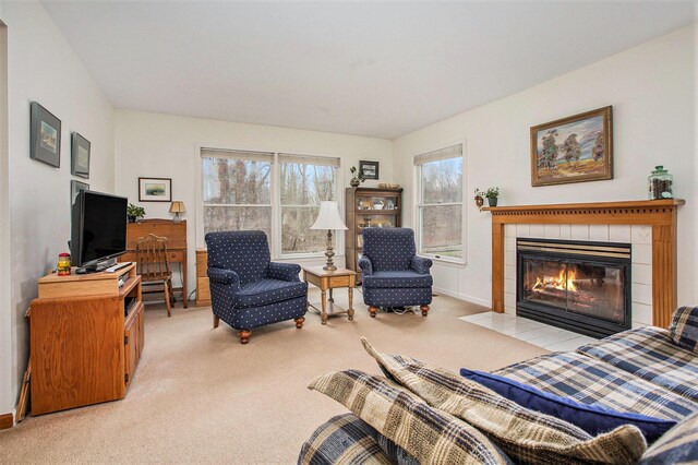 living room with carpet floors, baseboards, and a tiled fireplace