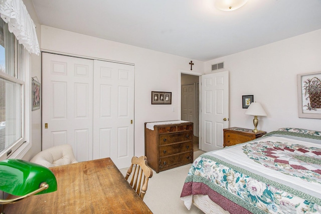 carpeted bedroom with visible vents and a closet