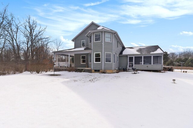 snow covered property with a sunroom and a porch