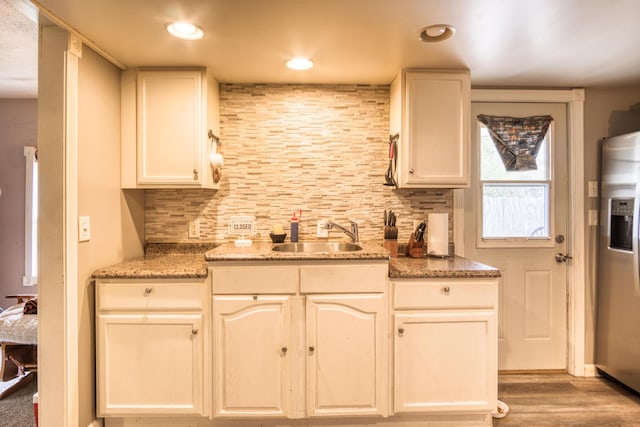321 N Norman St, Barryton, MI 49305 - kitchen featuring a sink, stainless steel refrigerator with ice dispenser, decorative backsplash, light wood-type flooring, and light stone countertops