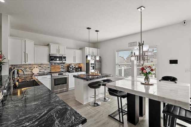 5922 Sable Ridge Dr SE, Kentwood, MI 49508 - kitchen with appliances with stainless steel finishes, a sink, tasteful backsplash, a breakfast bar area, and a center island
