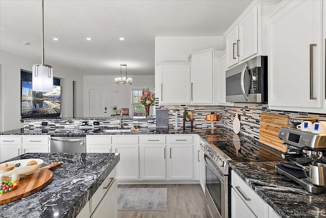 5922 Sable Ridge Dr SE, Kentwood, MI 49508 - kitchen featuring appliances with stainless steel finishes, light wood finished floors, white cabinets, backsplash, and a peninsula