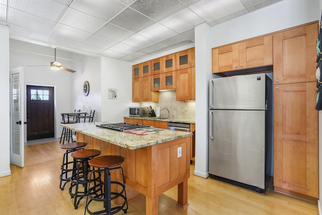 532 Dyckman Ave Unit B1A, South Haven, MI 49090 - kitchen featuring appliances with stainless steel finishes, light wood-style floors, a center island, and brown cabinetry