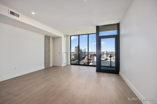 144 Oakes St SW Unit 1905, Grand Rapids, MI 49503 - empty room with a wall of windows, light wood finished floors, baseboards, visible vents, and a city view
