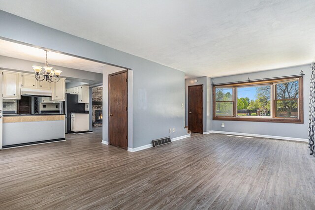 105 N Dr E, Marshall, MI 49068 - unfurnished living room with dark wood-style floors, a chandelier, and baseboards