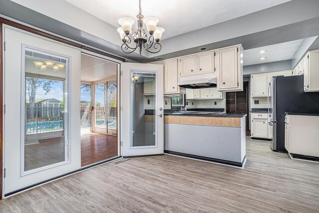 105 N Dr E, Marshall, MI 49068 - kitchen with under cabinet range hood, dark countertops, a chandelier, light wood-style floors, and recessed lighting