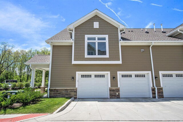 603 Woodland, Dexter, MI 48130 - view of front of home featuring concrete driveway, an attached garage, roof with shingles, and stone siding