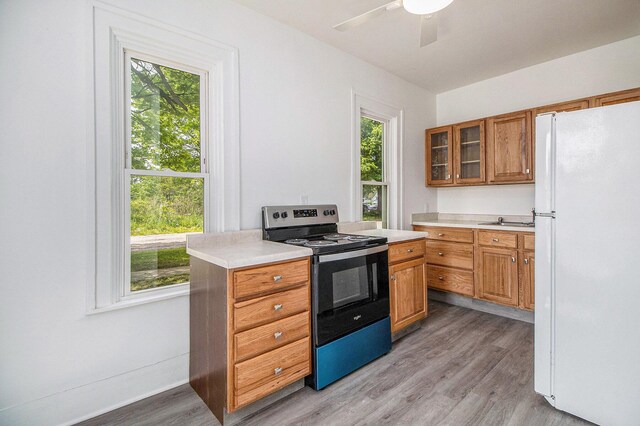 501 E Paw Paw St, Paw Paw, MI 49079 - kitchen featuring freestanding refrigerator, stainless steel electric range oven, light wood finished floors, brown cabinetry, and light countertops