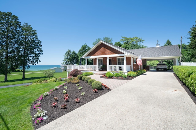 view of front facade with a porch, driveway, a front yard, a water view, and roof with shingles