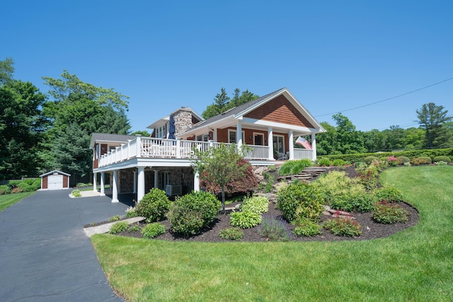 view of front of home with an outbuilding, a detached garage, a front yard, driveway, and central air condition unit