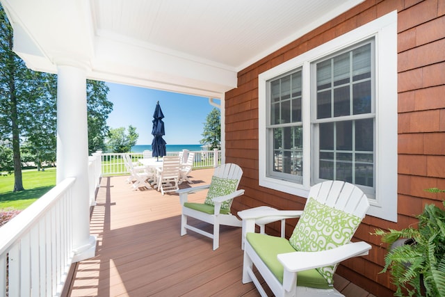 wooden terrace featuring a porch, a water view, and outdoor dining area