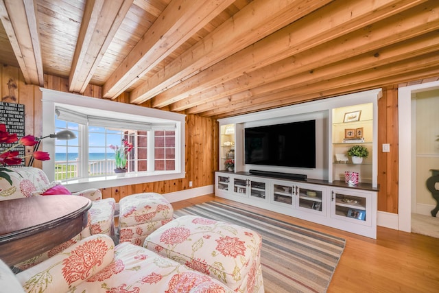 living area featuring wood ceiling, wood finished floors, beamed ceiling, baseboards, and wood walls