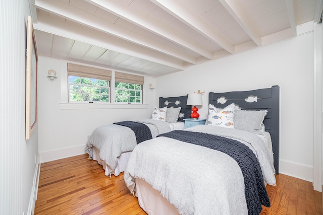 bedroom featuring beamed ceiling, wood finished floors, baseboards, and wood ceiling