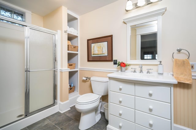 bathroom with toilet, a stall shower, a wainscoted wall, and vanity