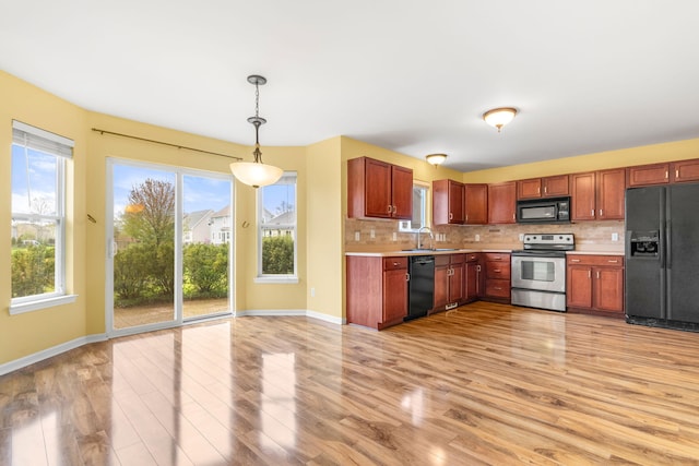kitchen featuring black appliances, a sink, light countertops, and light wood-type flooring