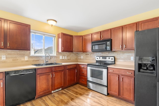 kitchen with black appliances, a sink, light wood-style floors, and light countertops