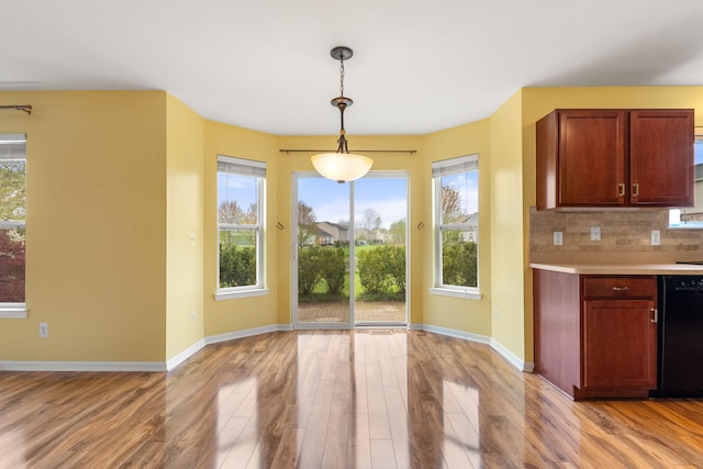 kitchen featuring black dishwasher, light wood-style floors, light countertops, baseboards, and pendant lighting