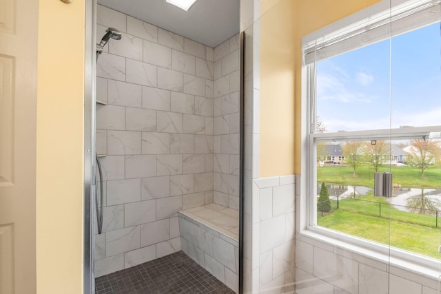 full bathroom featuring a water view, tiled shower, and healthy amount of natural light