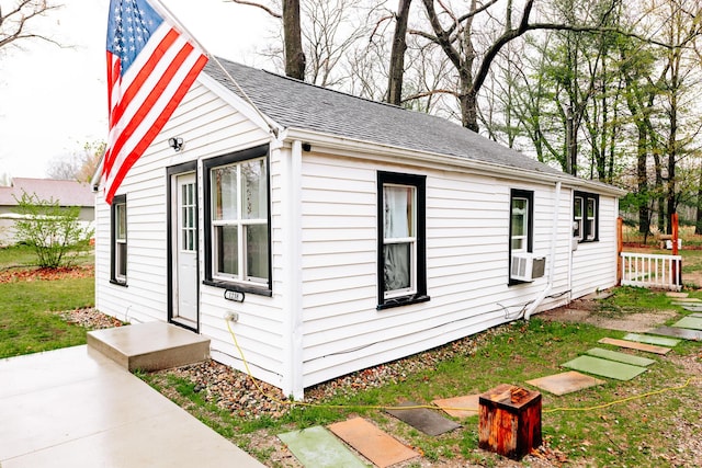 exterior space with a shingled roof and cooling unit