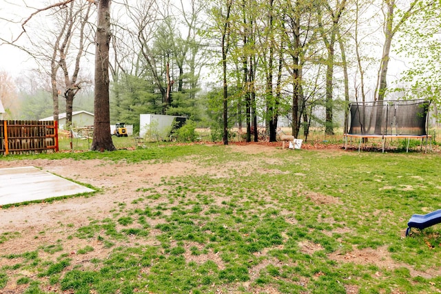 view of yard with a trampoline and fence