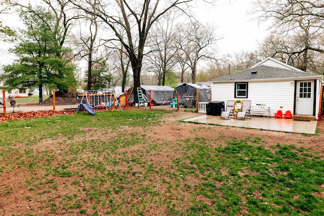 view of yard with an outdoor structure, a patio, a playground, and fence