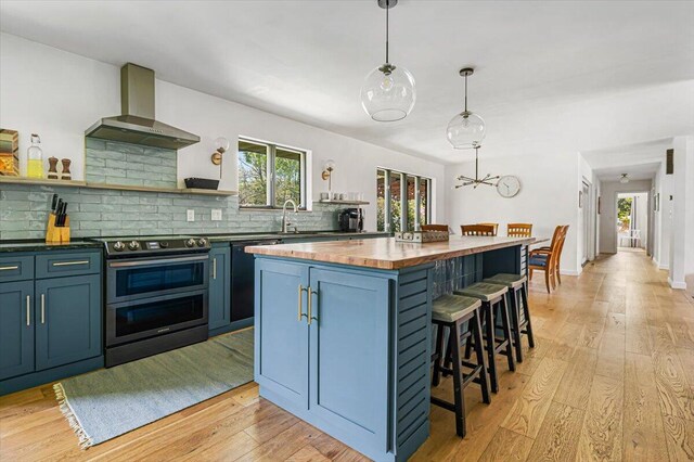 5407 Browntown Rd, Sawyer, MI 49125 - kitchen with range with two ovens, wall chimney exhaust hood, open shelves, blue cabinetry, and butcher block counters