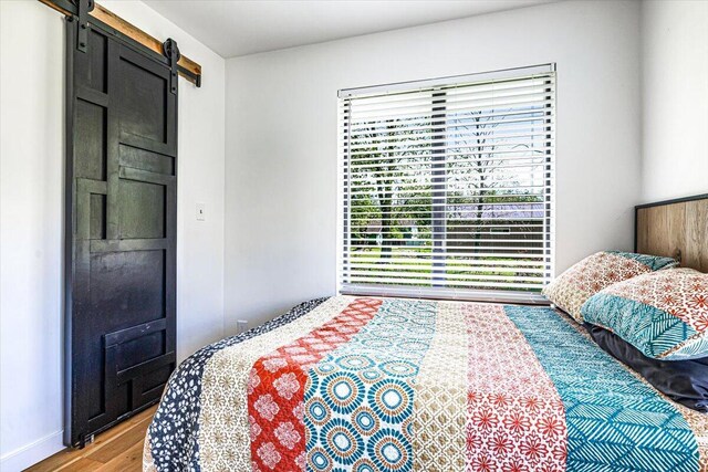 5407 Browntown Rd, Sawyer, MI 49125 - bedroom featuring multiple windows, a barn door, and light wood-style flooring
