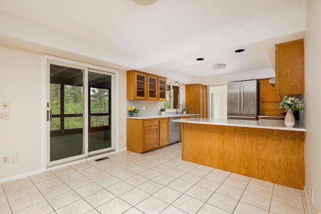 3949 Waldenwood Dr, Ann Arbor, MI 48105 - kitchen with appliances with stainless steel finishes, brown cabinets, light countertops, a peninsula, and glass insert cabinets