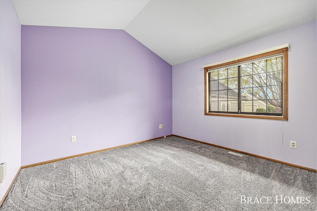 spare room featuring carpet floors, lofted ceiling, and baseboards