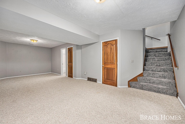 finished below grade area featuring a textured ceiling, carpet flooring, baseboards, and stairway