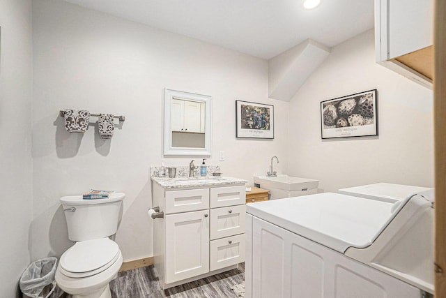 17389 Rapids Dr, Hersey, MI 49639 - bathroom with washing machine and clothes dryer, toilet, wood finished floors, vanity, and baseboards