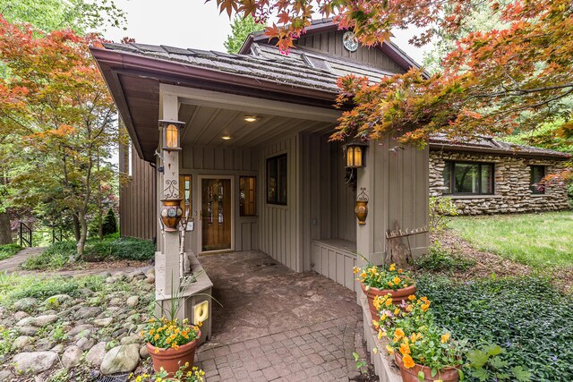 10985 E Pleasant Lake Rd, Manchester, MI 48158 - view of exterior entry with board and batten siding, a porch, and stone siding