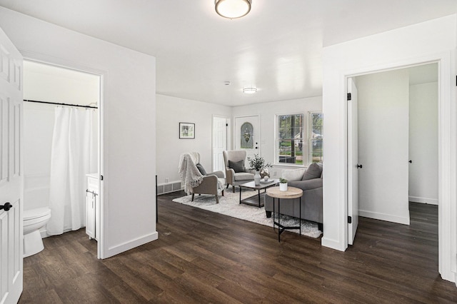 living area featuring visible vents, dark wood-style flooring, and baseboards