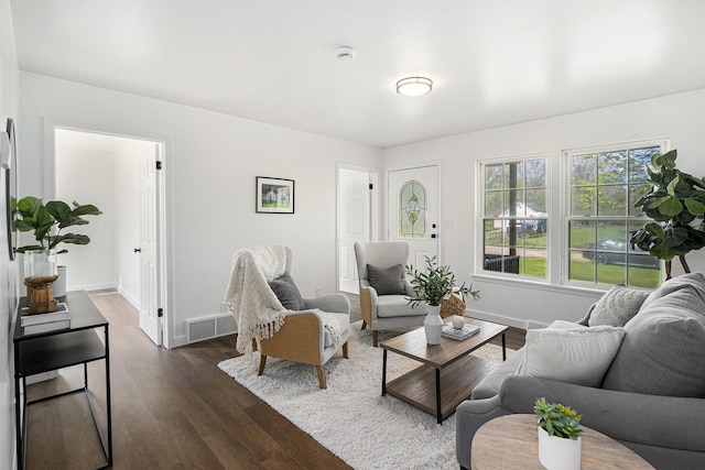 living room with visible vents, dark wood-style flooring, and baseboards