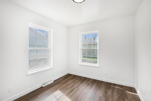 unfurnished room with baseboards, dark wood-style floors, a healthy amount of sunlight, and visible vents