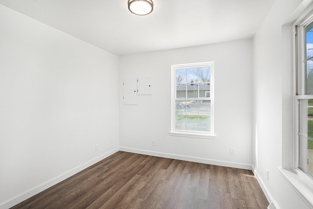 unfurnished room with baseboards and dark wood-style floors