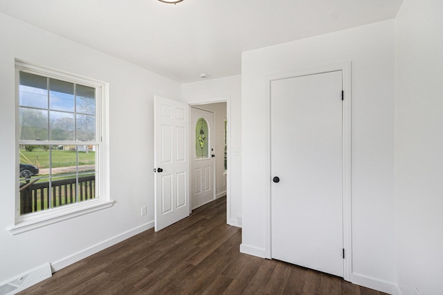 unfurnished bedroom featuring baseboards, visible vents, and dark wood-style floors