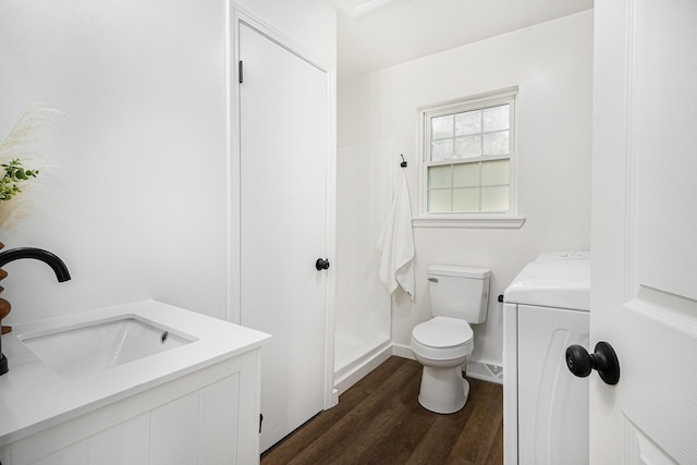 bathroom with washer / dryer, toilet, wood finished floors, and vanity