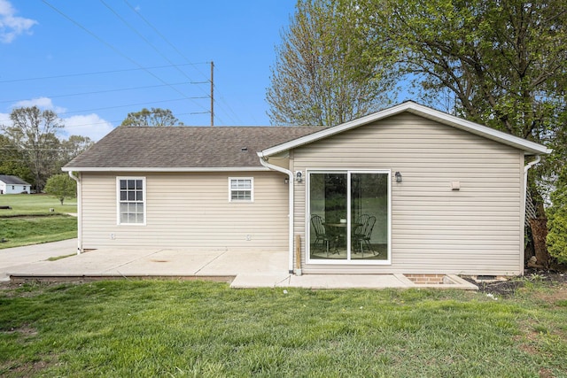 rear view of property with roof with shingles, a patio area, and a lawn
