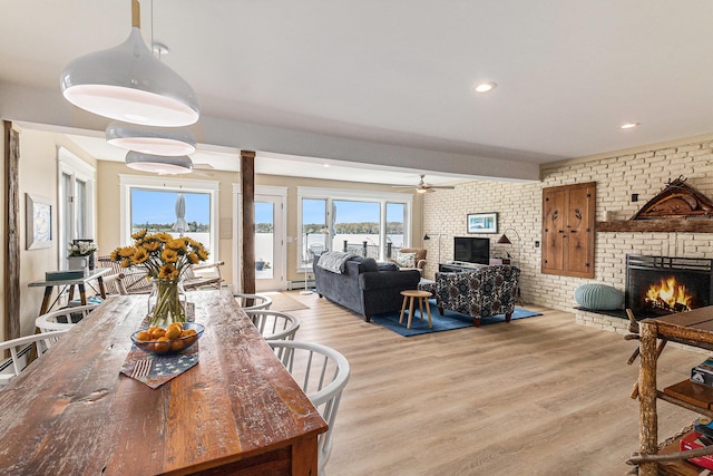 447 Paradise Ln, Horton, MI 49246 - dining room with a fireplace, light wood finished floors, brick wall, a ceiling fan, and recessed lighting