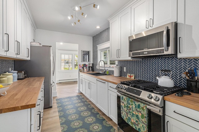 447 Paradise Ln, Horton, MI 49246 - kitchen featuring wood counters, stainless steel appliances, a sink, a baseboard heating unit, and backsplash